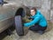 Young smiling woman driver changes car tyres