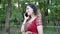 Young smiling woman in ethnic Indian red Sari talking on the phone in summer Park