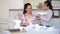 Young smiling woman and girl making airplanes of paper at home