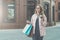 Young smiling woman in glasses carries shopping bags and holds cup of coffee.Girl bought presents for her friend.