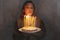 Young smiling woman holding homemade birthday cake pie with burning candles