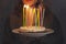 Young smiling woman holding homemade birthday cake pie with burning candles