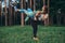 Young smiling woman lifting her friend on her back having fun while training in forest