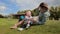 Young smiling woman lying on grass at park and playing with her 1 year old boy