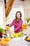 Young smiling woman making smoothie with fresh greens in the blender in kitchen at home