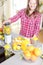 Young smiling woman making smoothie with fresh greens in the blender in kitchen at home