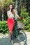 Young smiling woman rides a bicycle with a basket full of flower