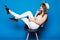 Young smiling woman sitting on chair on Blue background.