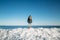 Young smiling woman standing on the top of sea ice blocks on the coast with a blue sea and sky and the background.