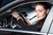 Young smiling woman in suit sitting in drivers seat of a passenger car and looking