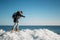 Young smiling woman walking on a top of frozen sea ice blocks on a coast of the sea with a blue sky at the background