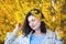 Young smiling woman in yellow blooming forsythia branches in spring outdoor