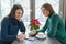 Young smiling women talking in cafe in winter season, with fresh coffee, smartphone, Christmas red poinsettia flower on the table