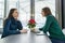 Young smiling women talking in cafe in winter season, with fresh coffee, smartphone, Christmas red poinsettia flower on the table