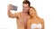 Young social media obsessed couple taking selfies in front of white background