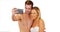 Young social media obsessed couple taking selfies on white background