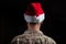 Young soldier wearing santa hat standing on black background