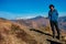 Young solo trekker with bamboo walking stick in the Himalayan hills, backdrop of glacial peaks. Uttarakhand, India. Adventurous