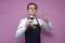 Young sommelier guy checks the smell of red wine on a colored background, an expert on wine in a white shirt and apron holds a