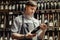 Young sommelier holding bottle of red wine in cellar