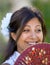 Young Spanish girl or woman smiling at camera holding traditional fan