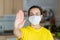 Young Spanish woman in protective sterile medical mask on her face looking at camera at home