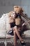 Young spoiled aristocrat sitting on vintage sofa. Blond lady playing with her huge teddy bear