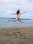 The young sport girl in swimsuit jumps high near Athlantic ocean