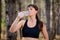 Young Sport Woman Drinking Water During Running in Beautiful Wild Pine Forest. Active Lifestyle Concept.