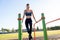 Young sportive athlete woman doing fitness exercise on metal bars outdoors at stadium court