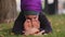 Young sportive calm mindful buddhist girl in hijab sits on green grass in park outdoors doing stretching bends in body