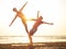 Young sportive couple girl and boy are practicing acroyoga exercises in the sunset on the beach