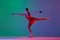 Young sportive girl, junior female figure skater in red stage costume skating isolated over gradient green-blue