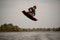 young sportive guy wakeboarder jumping high over river water
