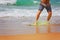 Young sportive man is running after his yellow and blue skimboard on the beach on a sunny day