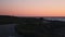 Young sportive woman running on empty promenade along mediterranean sea at sunset, rear view. Silhouette of woman runs along seash