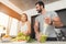 Young sports couple is preparing in the morning in the kitchen. A man is making a green vegetable cocktail.