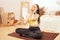 Young sports girl in beige interior. Yellow grey clothing. A healthy lifestyle. A woman does yoga, sits in a lotus position. Home