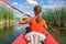 A young sports girl floats on the Zdwyzh River on a red kayak with  black dog Cocker Spaniel. Ukraine