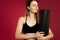 Young sports girl with headphones and closed eyes posing on cherry background. On the shoulder the girl holds a yoga mat