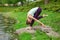 A young sports girl practices yoga on a green lawn by the river, yoga asana posture. Meditation and unity with nature