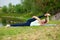 A young sports girl practices yoga on a green lawn by the river, yoga assans posture. Meditation and unity with nature