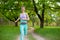 A young sports girl running in a quit green summer forest. Sport and wellness