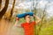 Young sports man in red t-shirt posing in a spring park with a blue yoga mat. He holds a yoga mat over his head