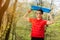 Young sports man in red t-shirt posing in a spring park with a blue yoga mat. He holds a yoga mat over his head