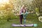 Young sports mother doing physics exercise outdoors in garden near her daughter. Healthy lifestyle. Yoga. Fitness