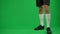Young sportsman jumping up passing football ball at chromakey background. Unrecognizable Caucasian man making soccer