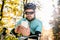 Young sportsman riding bicycle, holding smartphone, sunny autumn