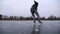 Young sportsman shod in figure skates sliding on ice river at winter. Male skater practicing skills at lake on frozen