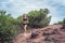 Young sportswoman cross country running on dirty rocky footpath in mountains in summer. Fit girl jogging outdoors in